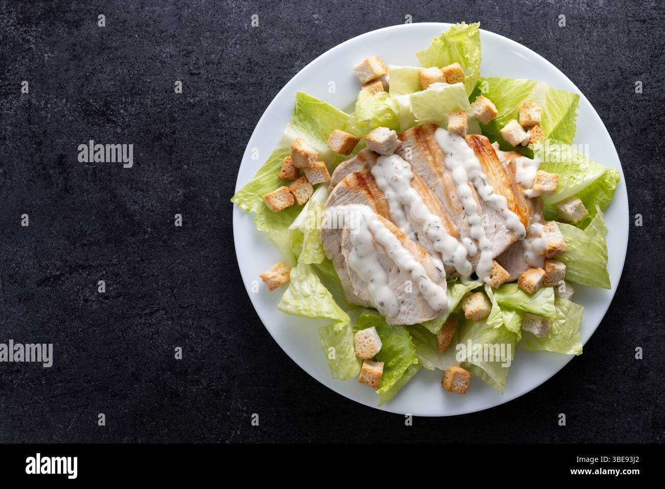 Classic Caesar Salad Fresh and crunchy Caesar salad on black slate background Stock Photo