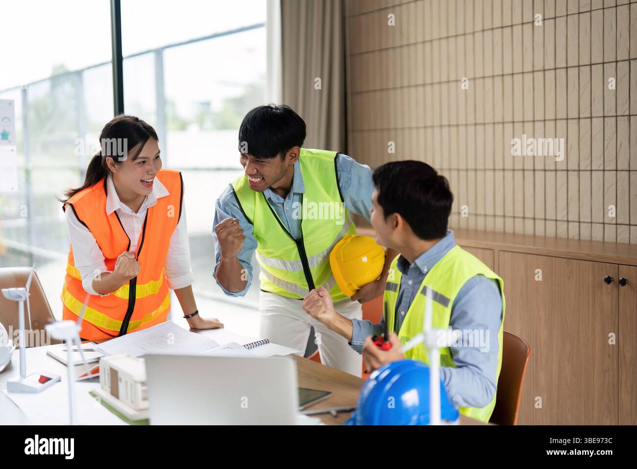 Green Tech Team Celebration. Engineers celebrating a successful project in a collaborative environment. Stock Photo