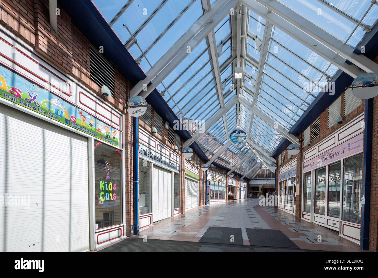 Modern shopping centre with rows of closed outlats looking like a ghost town In Prescot, Merseyside. Stock Photo