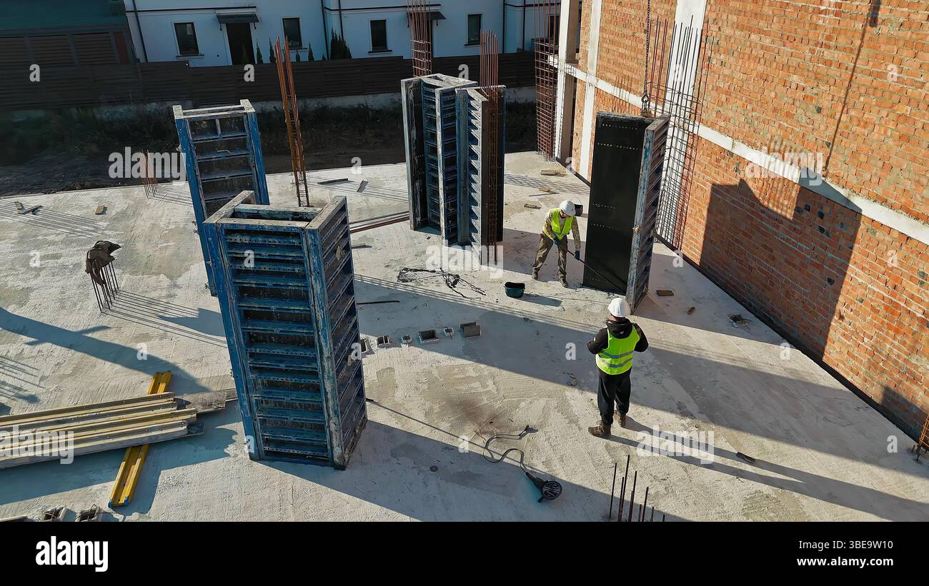 Construction workers assembling formwork for concrete columns on a ...