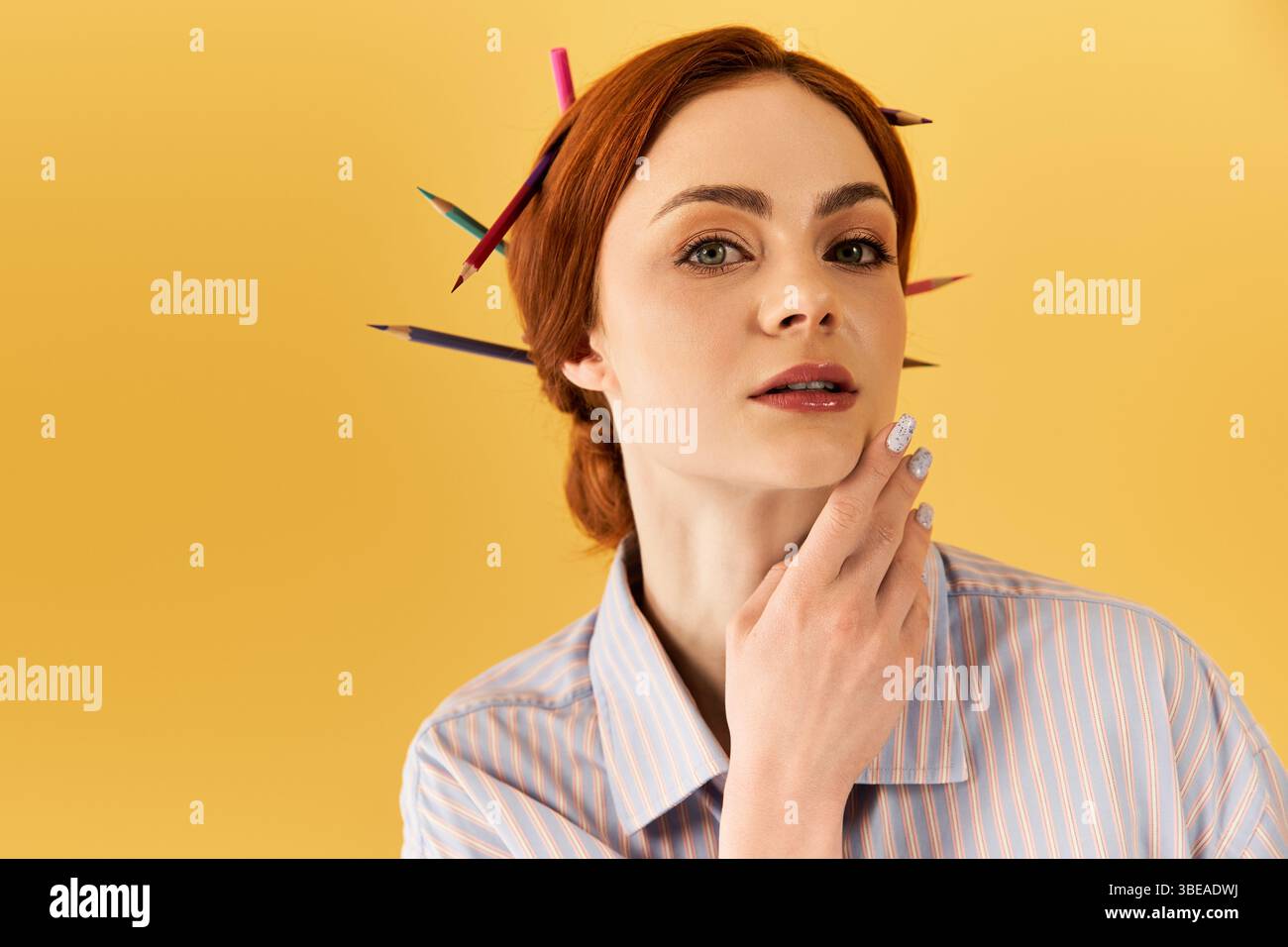 A young woman with red hair poses with vibrant pencils, showcasing her artistic spirit. Stock Photo