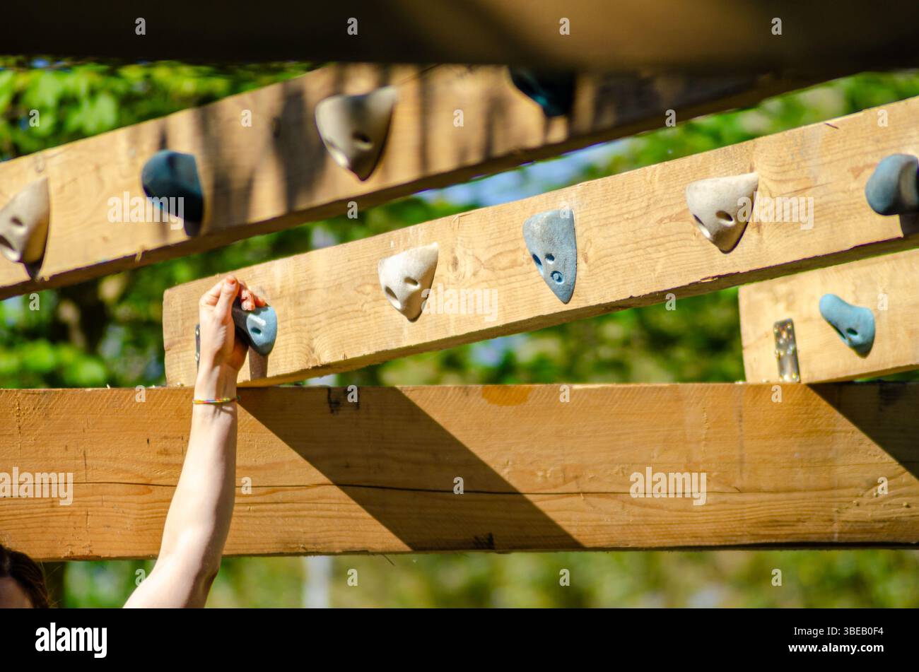 overcoming challenge: hand gripping firmly on wooden obstacle course Stock Photo