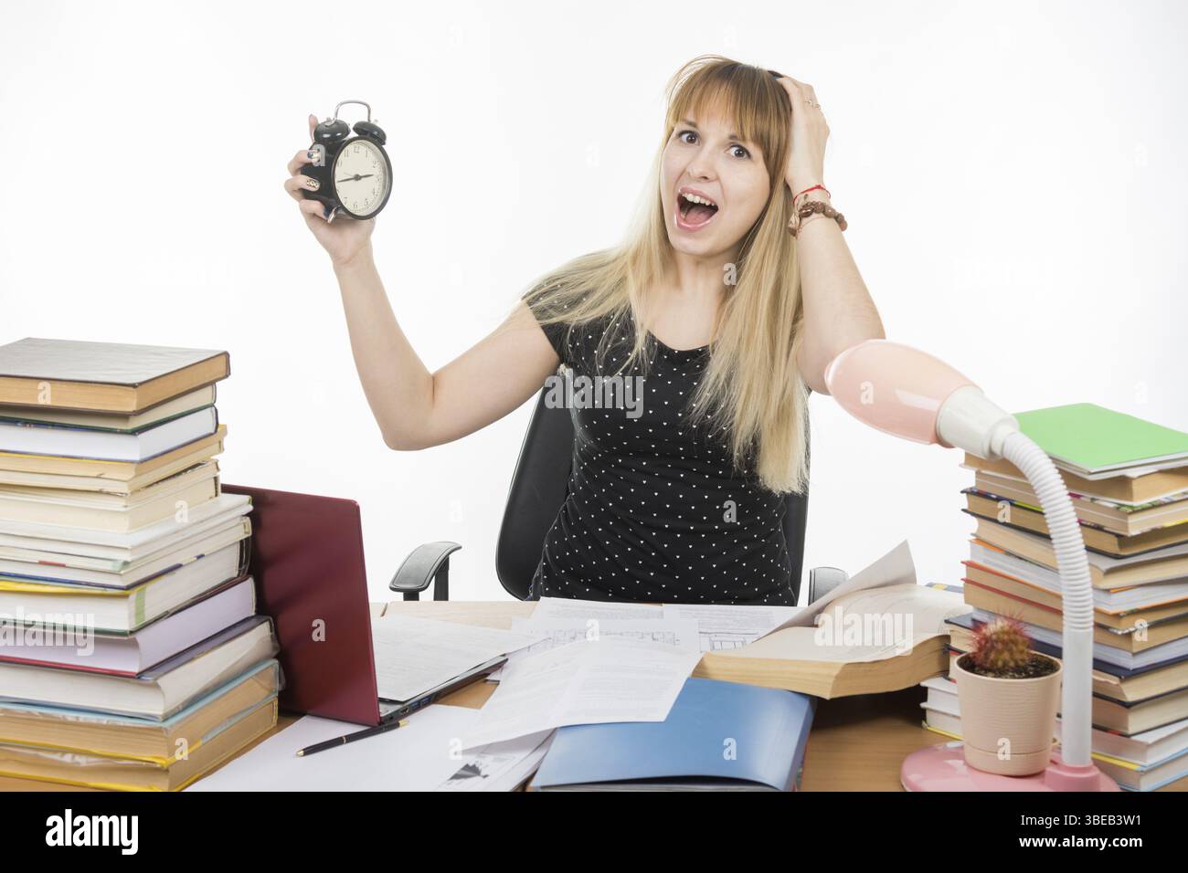 A student with an alarm clock in hands understand that slept exam Stock Photo