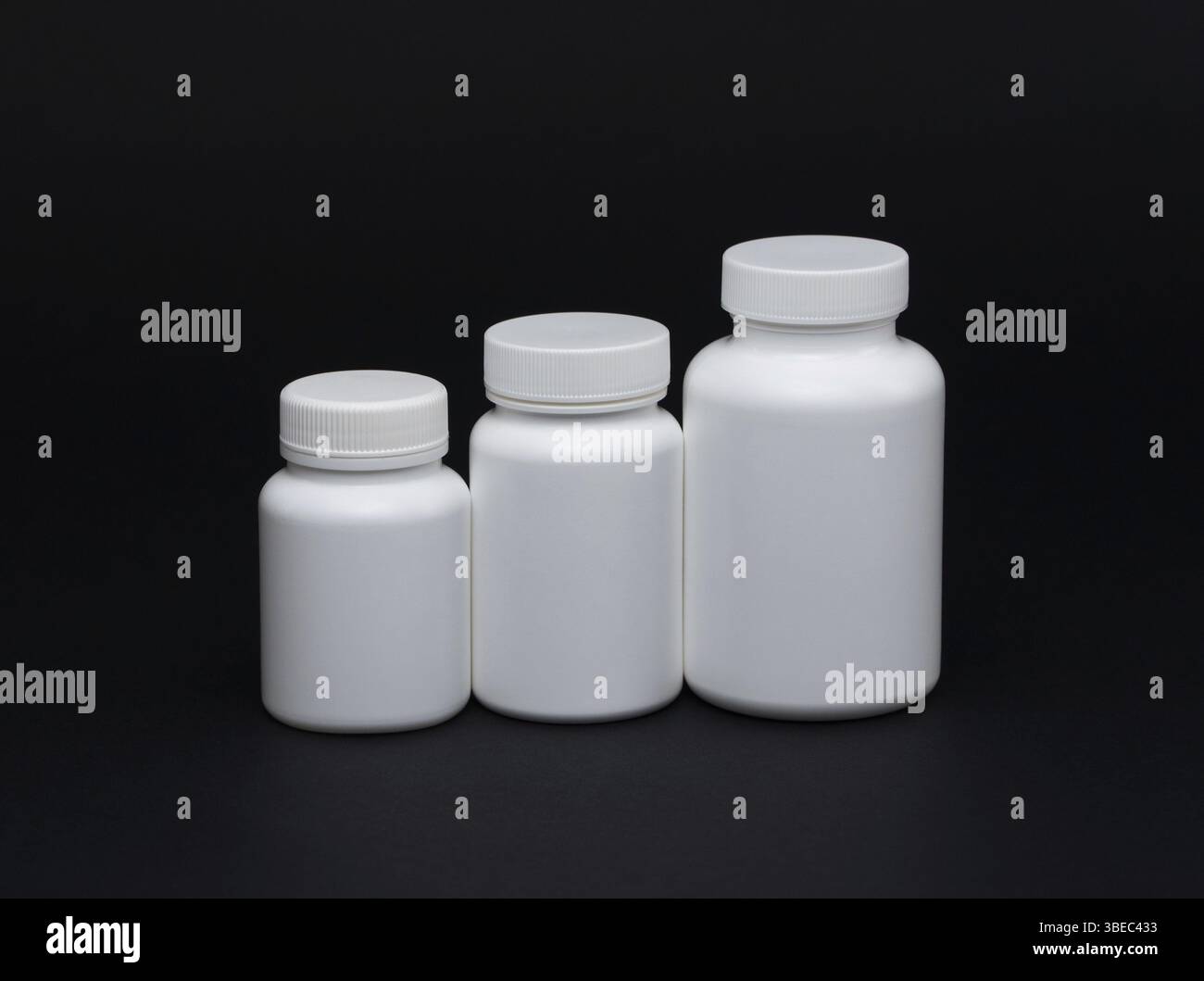White plastic pill jars on a black background. Isolated Stock Photo