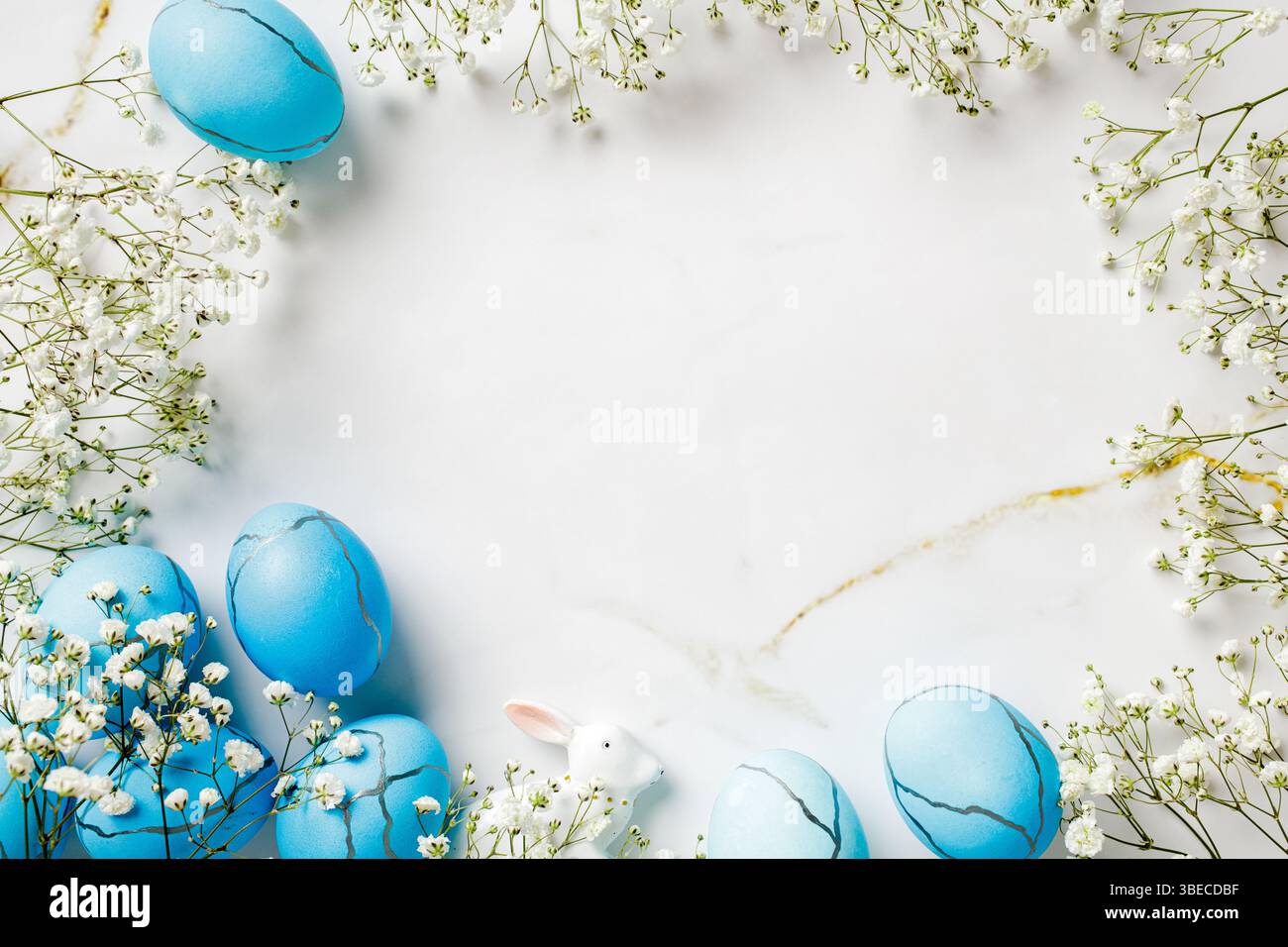Easter scene with blue Easter eggs with flowers on marble table. Top view. Stock Photo