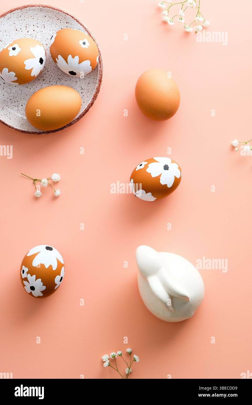 Happy Easter flat lay composition. Easter eggs, spring flowers, Easter bunny rabbit on pastel pink background. Minimal style. Stock Photo