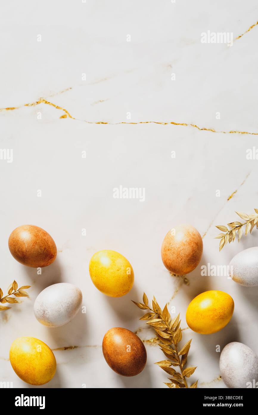 Luxury Easter vertical flat lay composition. Elegant Easter eggs with golden branches on marble table. Stock Photo