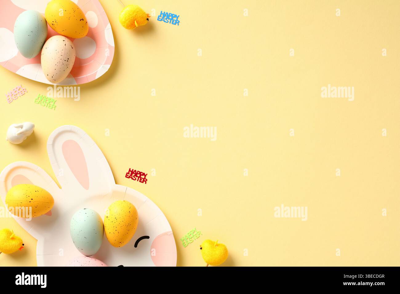 Happy Easter composition. Flat lay Easter eggs and table serving cutlery on yellow background. Stock Photo