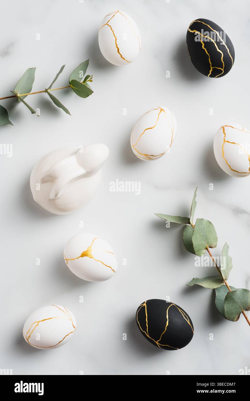 Easter flat lay composition with luxury easter eggs, bunny rabbit, eucalyptus leaves on marble background. Stock Photo