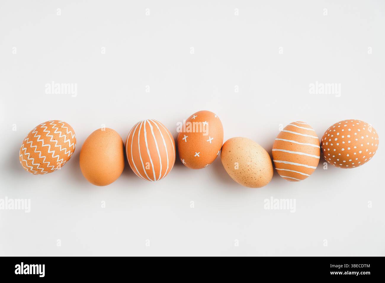 Painted Easter eggs in row on white background. Flat lay, top view. Elegant, simple, modern style. Stock Photo