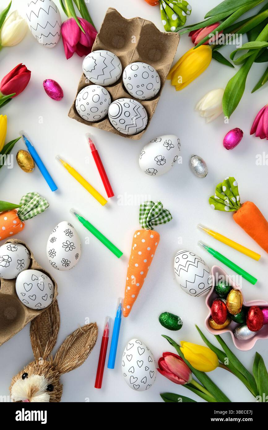 Happy Easter flat lay composition with Easter eggs for coloring, markers, tulips, Easter bunny on white background Stock Photo