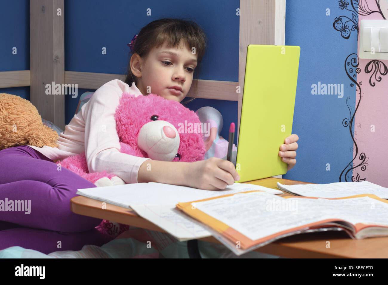 Girl in the evening does homework at home using a tablet computer Stock Photo