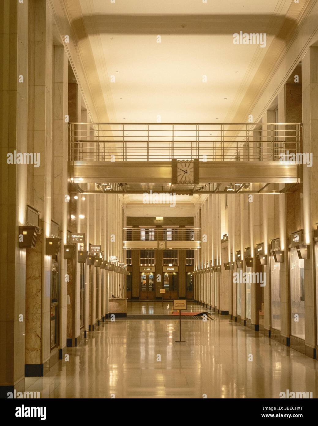 A quiet, well-lit hall with a clock and elevator signs is shown in an elegant building interior, Chicago, Illinois. Stock Photo