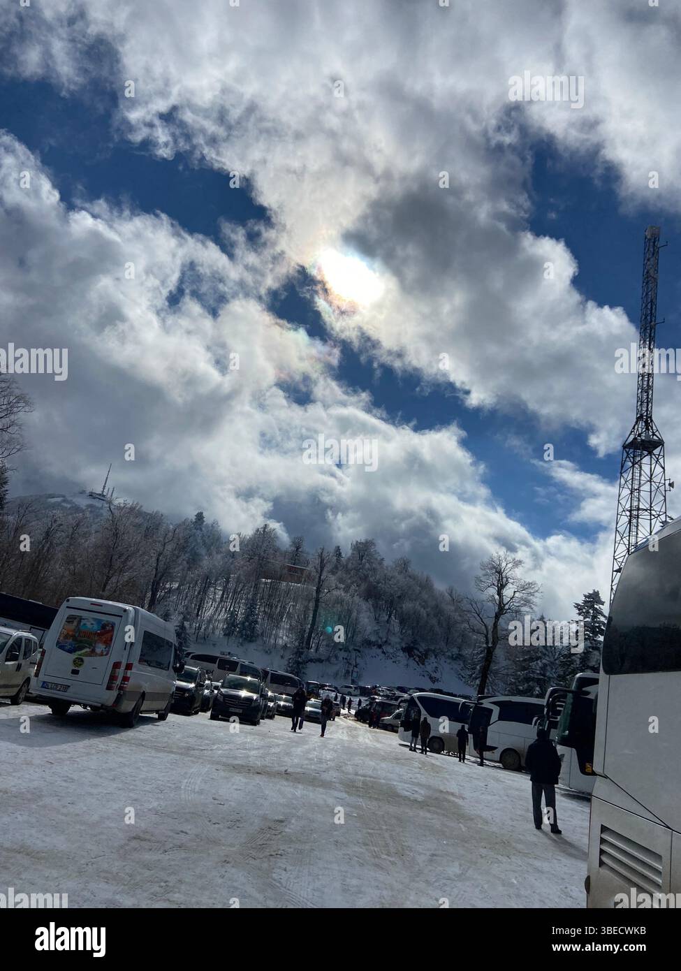 Snowy urban scene with parked cars, people walking, and dramatic cloudy sky in Istanbul. - Smartphone Captured Stock Image