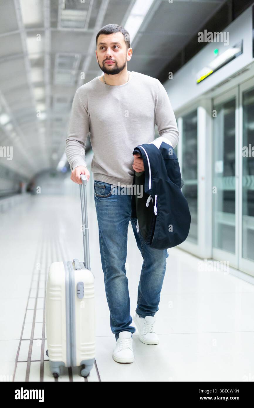 Young man walking through metro station with suitcase Stock Photo