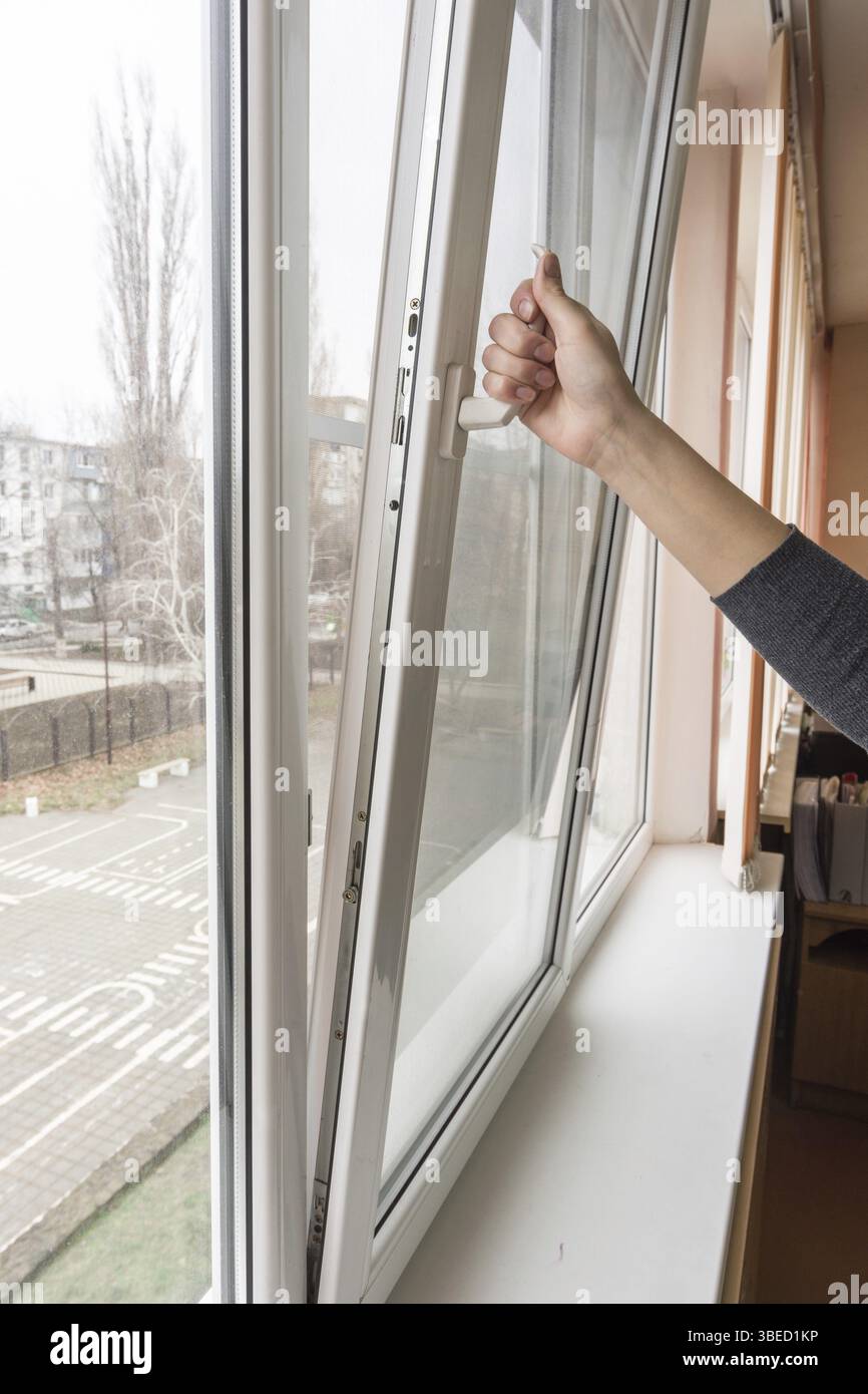 A hand opens a plastic window in a school class Stock Photo