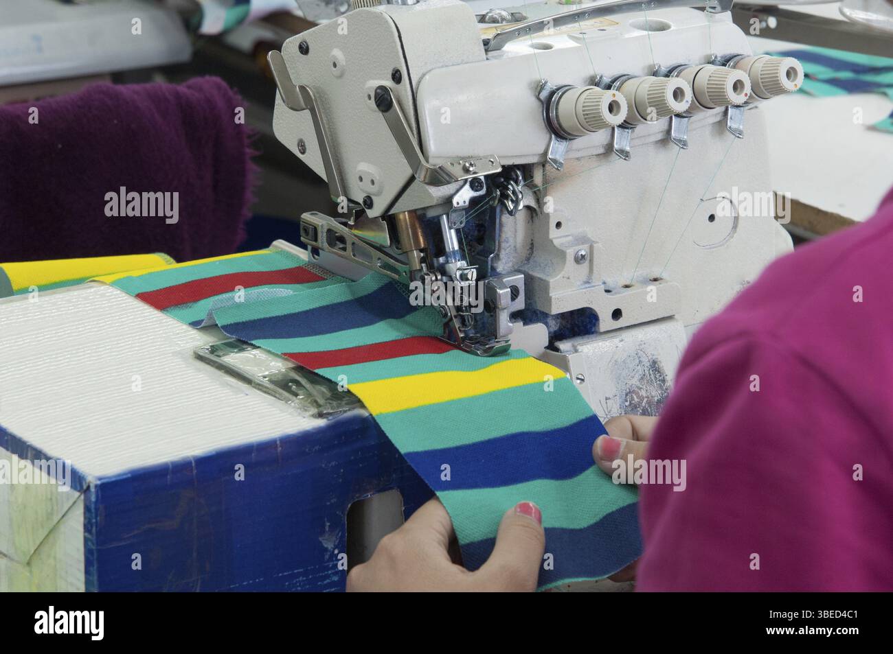Closeup seamstress on the machine sews clothes at a garment factory Stock Photo
