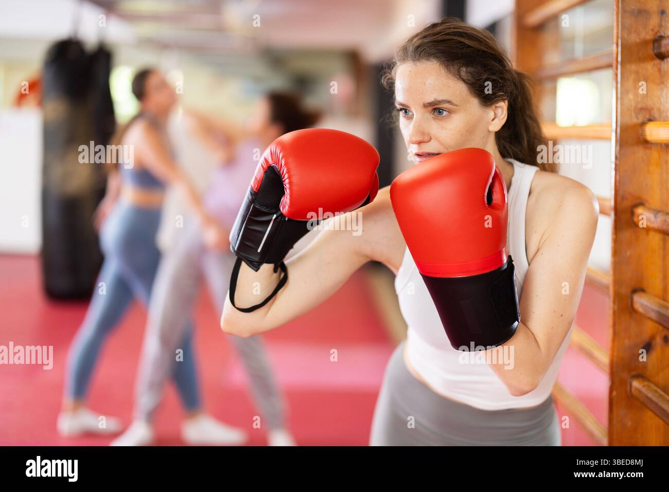 Woman practices punch with boxing gloves Stock Photo