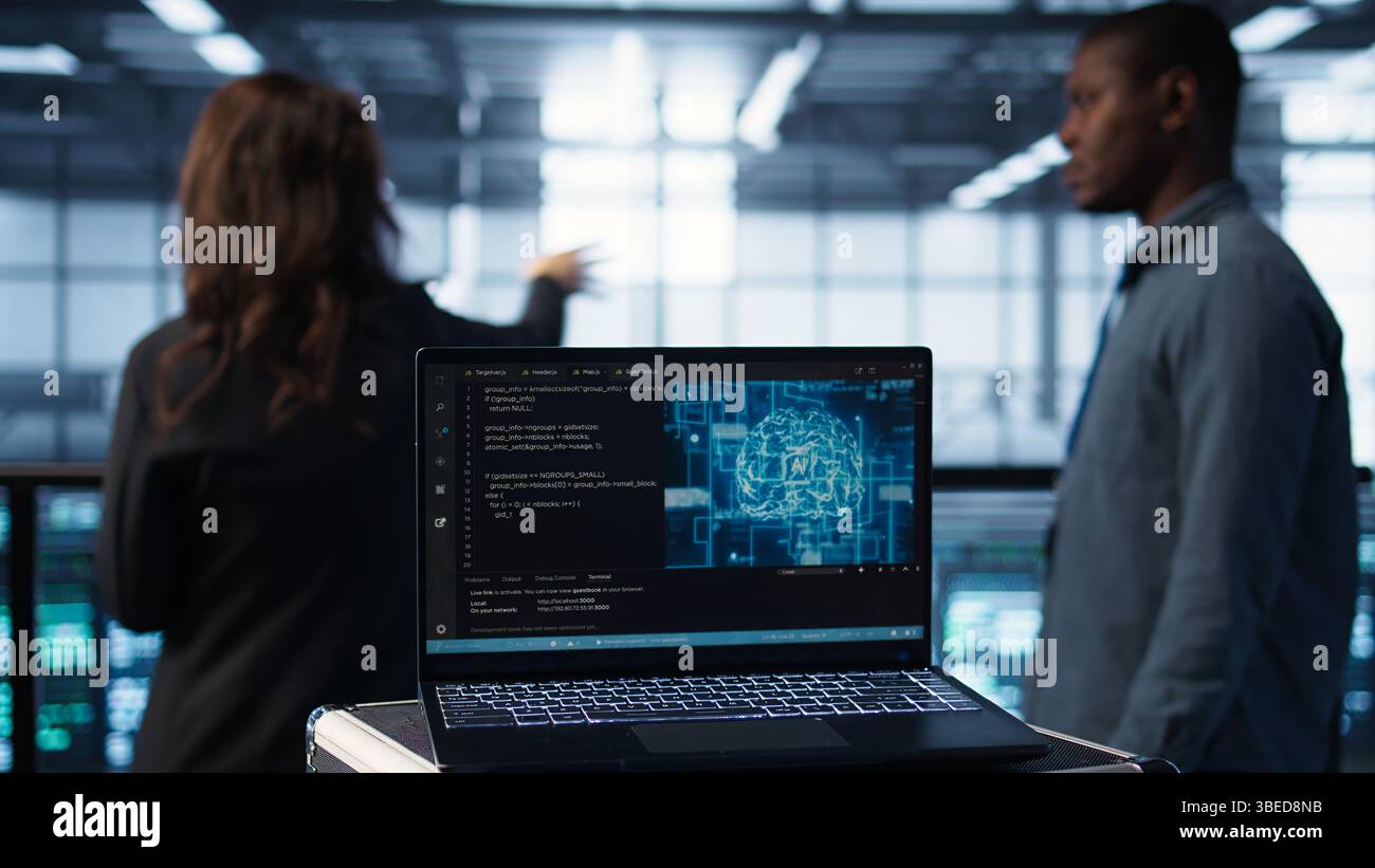 Focus on laptop used by teamworking data center computer scientists in background using artificial intelligence. Notebook screen with neural networks doing computing processes, camera B close up Stock Photo