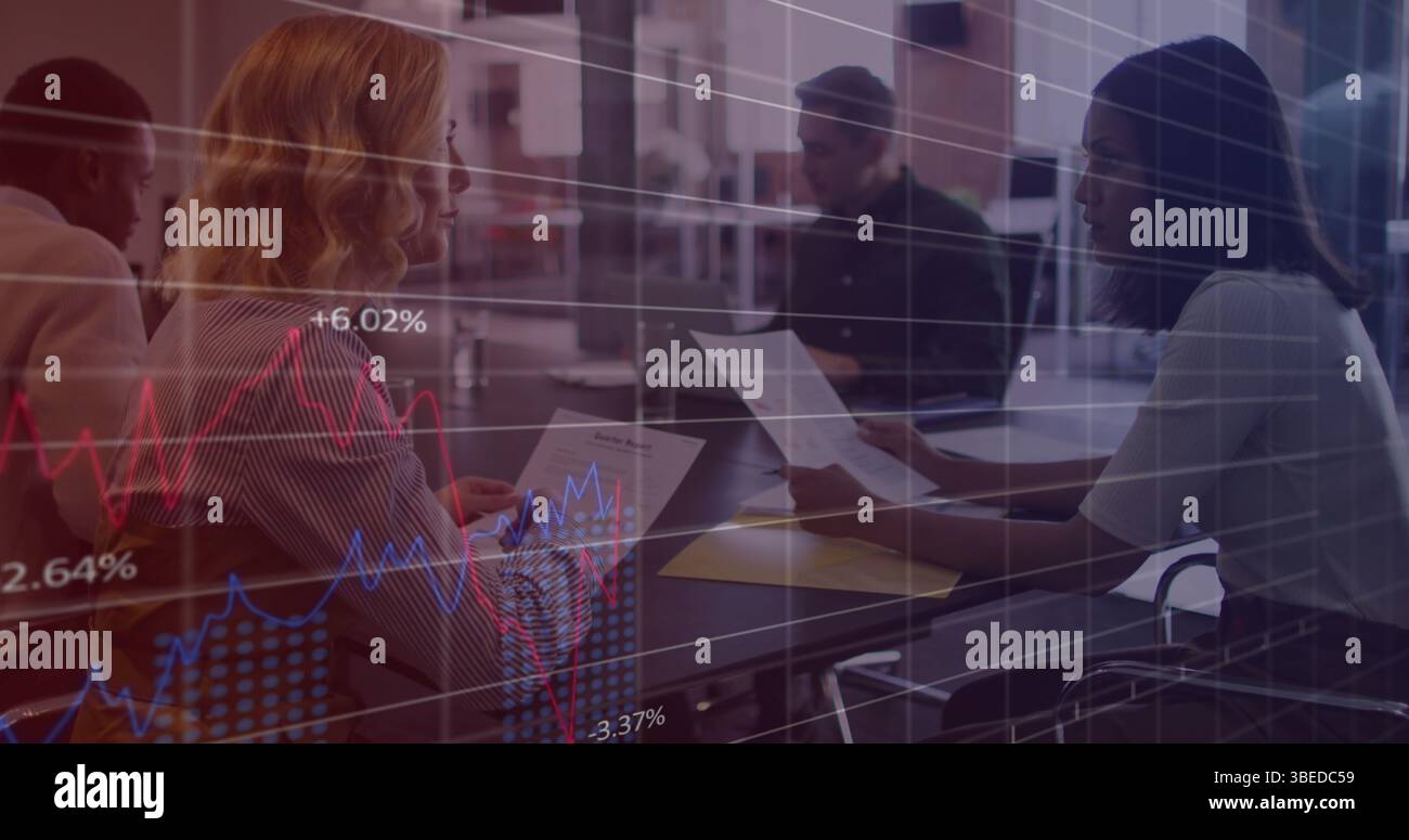 Statistical data processing against two diverse female office colleagues discussing at office Stock Photo