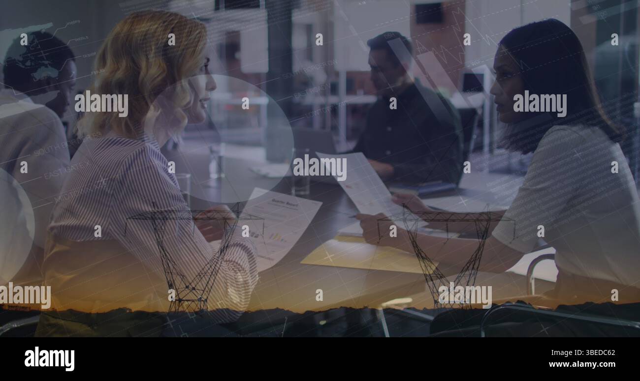 Statistical data processing against two diverse female office colleagues discussing at office Stock Photo