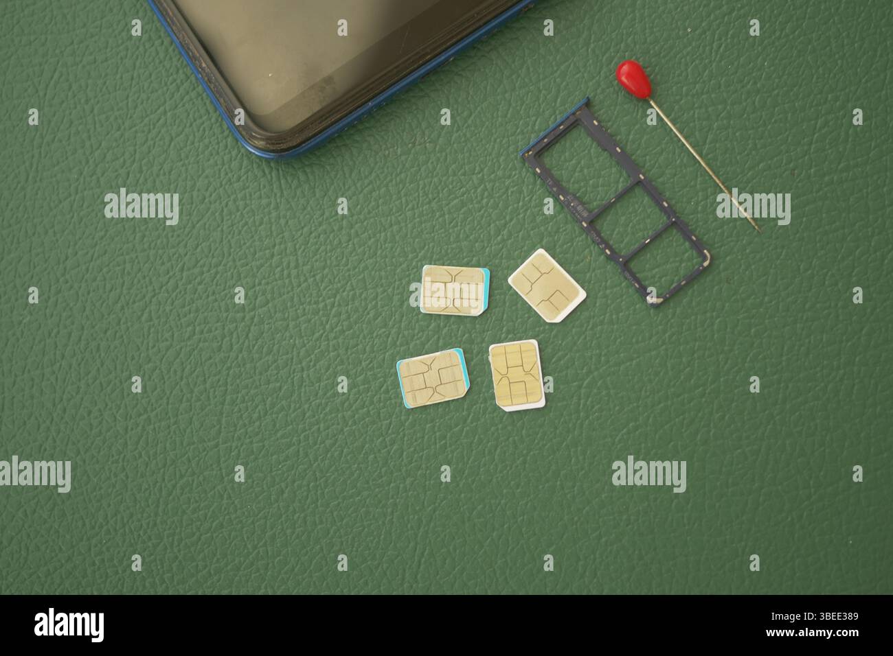 Multiple SIM cards and a tray placed on a green surface Stock Photo