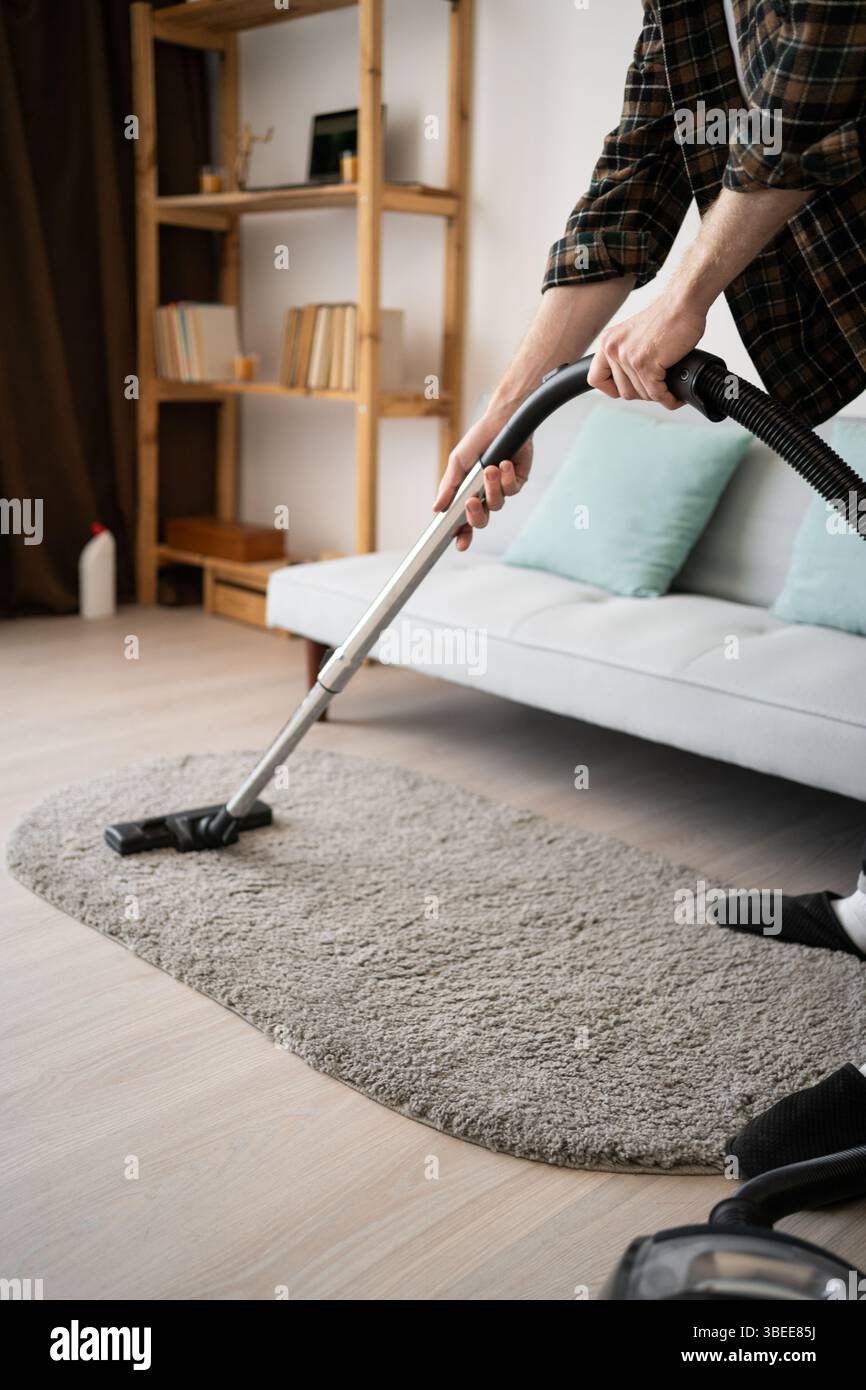 Cleaning concept. Man vacuuming carpet using vacuum cleaner, close-up Stock Photo
