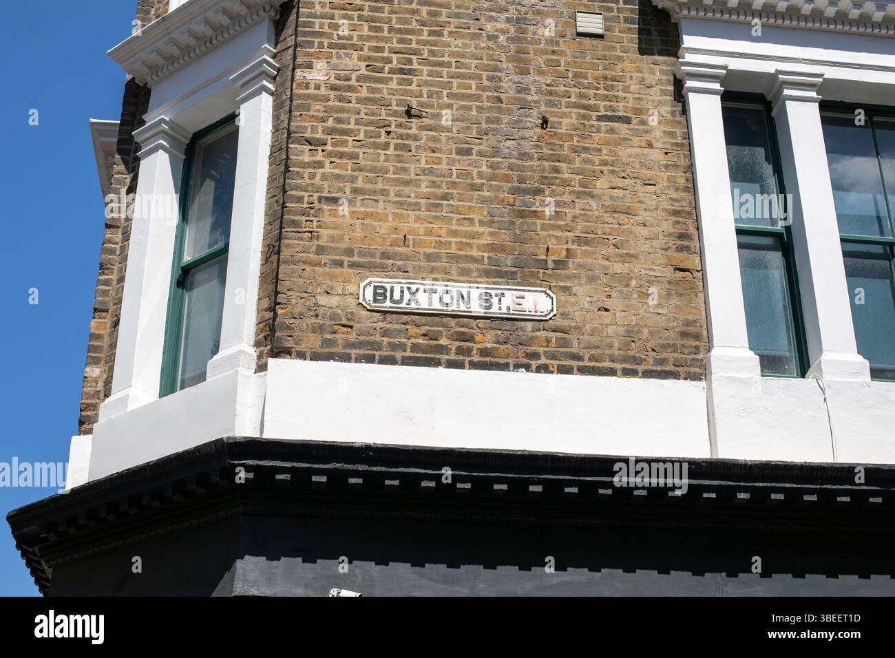 A street sign for Buxton Street on a brick building in London. Features ...