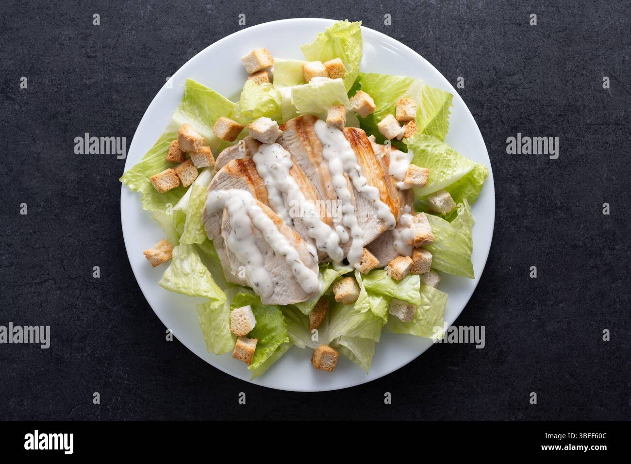 Classic Caesar Salad Fresh and crunchy Caesar salad on black slate background Stock Photo