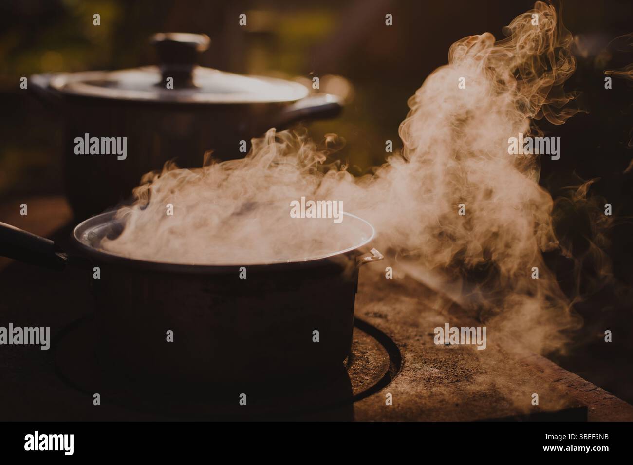 Vapor rising form water boiling in a steel pot placed on a fire stove ...