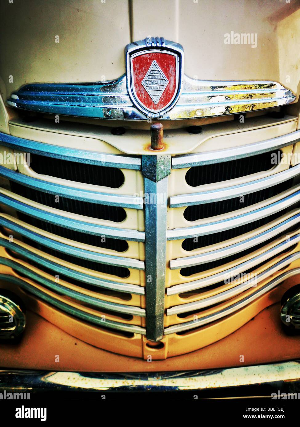 The front grille of a vintage truck features intricate chrome detailing with a prominent emblem. The weathered appearance reflects years of use - Smartphone Captured Stock Image