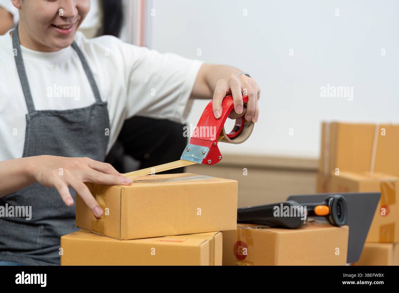 Couple packaging orders with tape and teamwork Stock Photo - Alamy