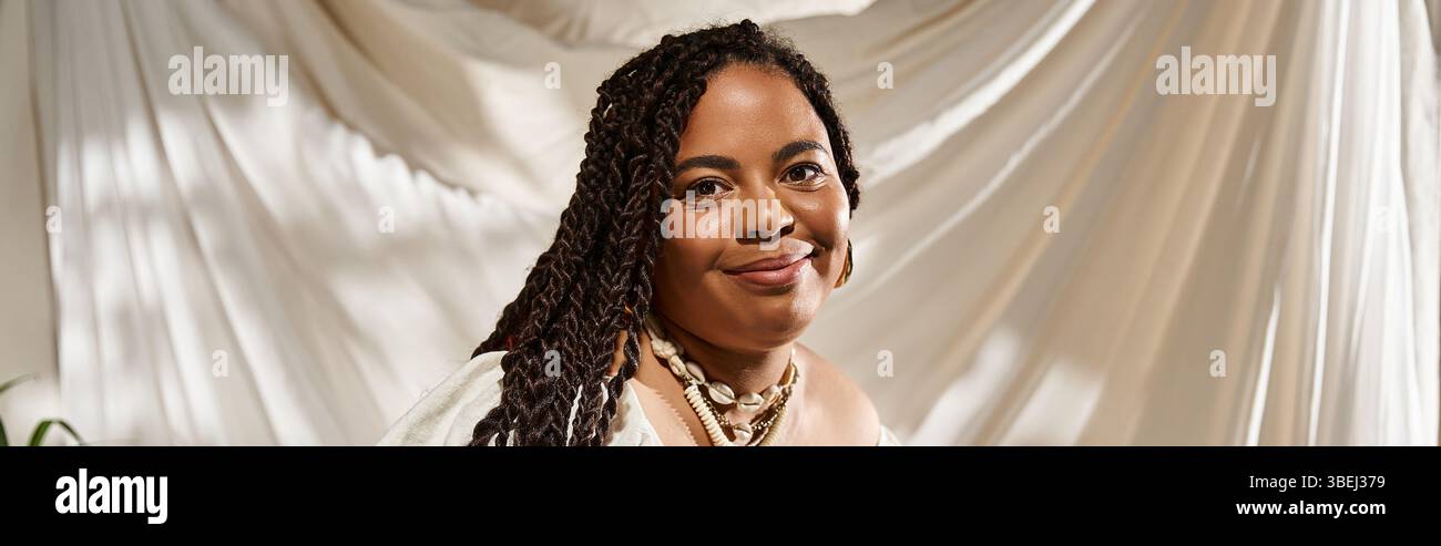 A joyful African American woman with braids poses amid lush green ...