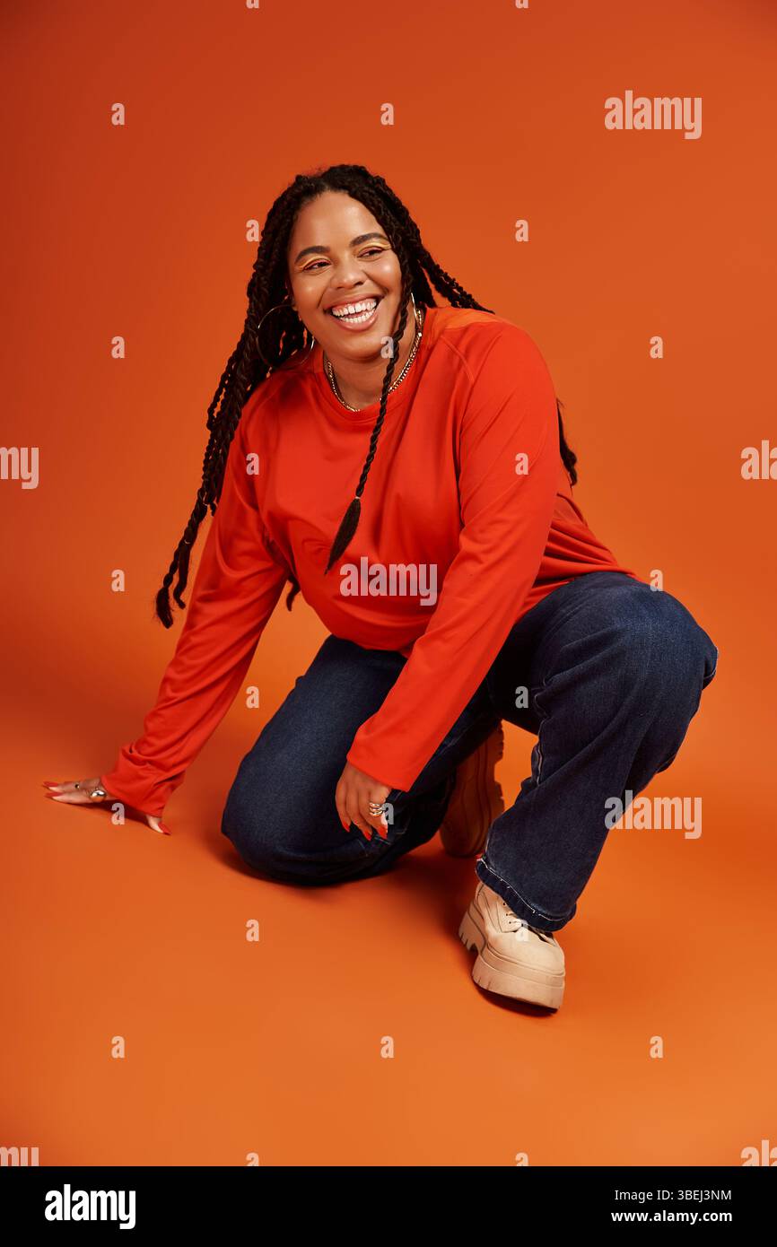 A joyful African American woman with braids poses playfully in a casual ...