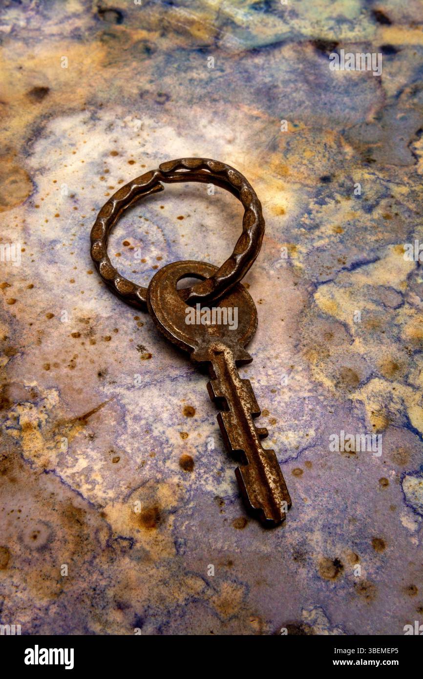 An aged key lies on a beautifully textured surface, showcasing its unique design and patina. Stock Photo