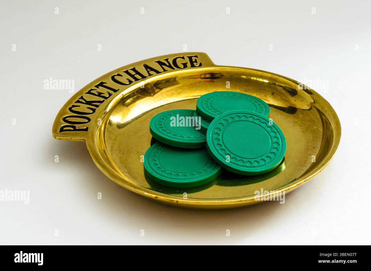 Brass Pocket Change tray with a pile of poker chips on a white background. Stock Photo