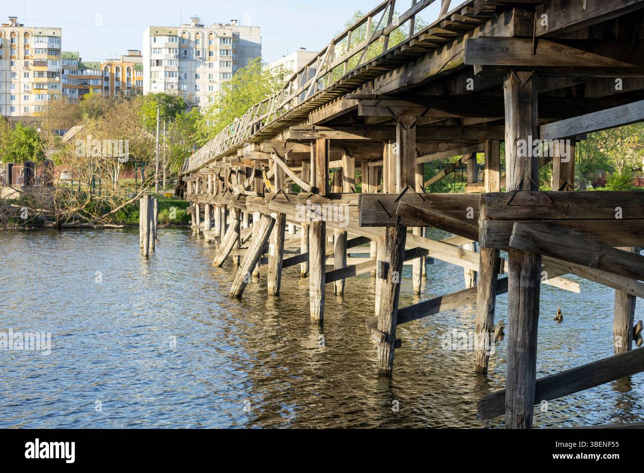 A charming wooden pedestrian bridge stretches across the river, its ...