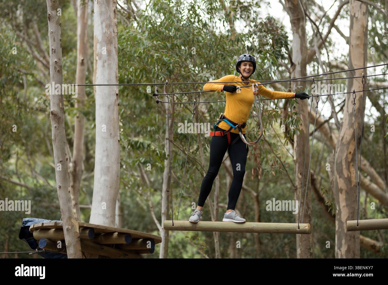 Woman wearing helmet, harness holding cable chains balancing on hanging ...