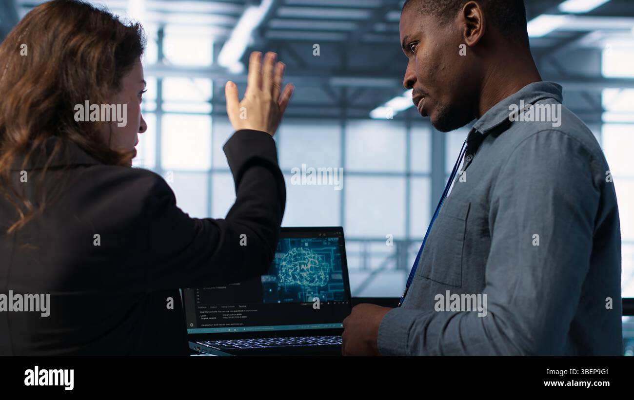 Software developers using AI tech on laptop in data center managing server virtualization. IT expert coding on notebook in server room using artificial intelligence, finetuning network, camera A Stock Photo