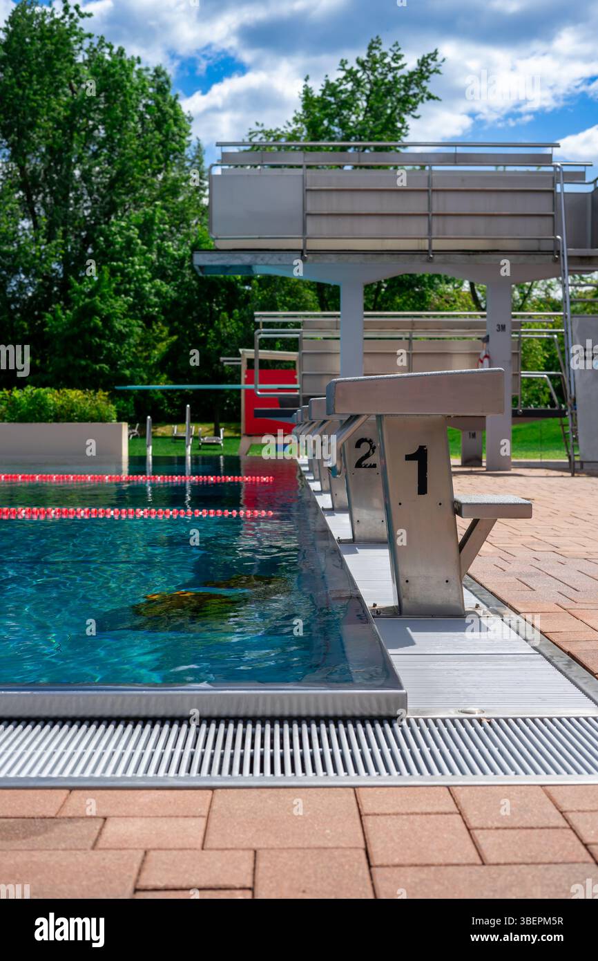 The diving tower in an outdoor swimming pool with green trees in the ...