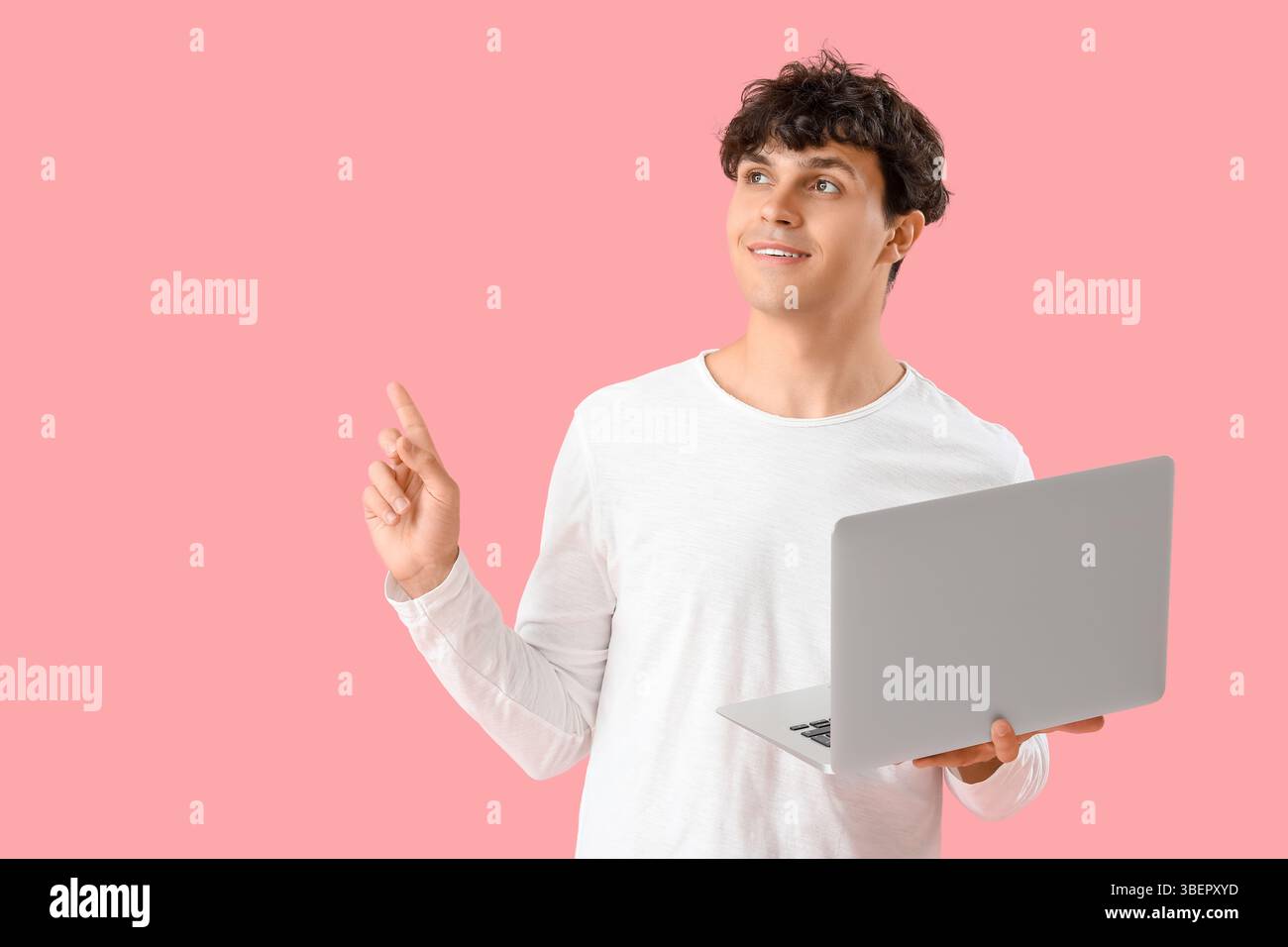 Male programmer with laptop pointing at something on pink background Stock Photo