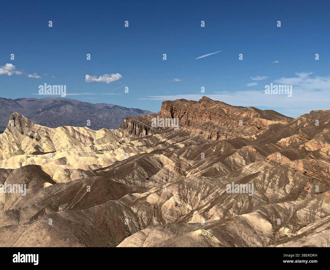 Panoramic view of Zabriskie Point's eroded badlands under a blue sky in Death Valley National Park, California, USA. - Smartphone Captured Stock Image