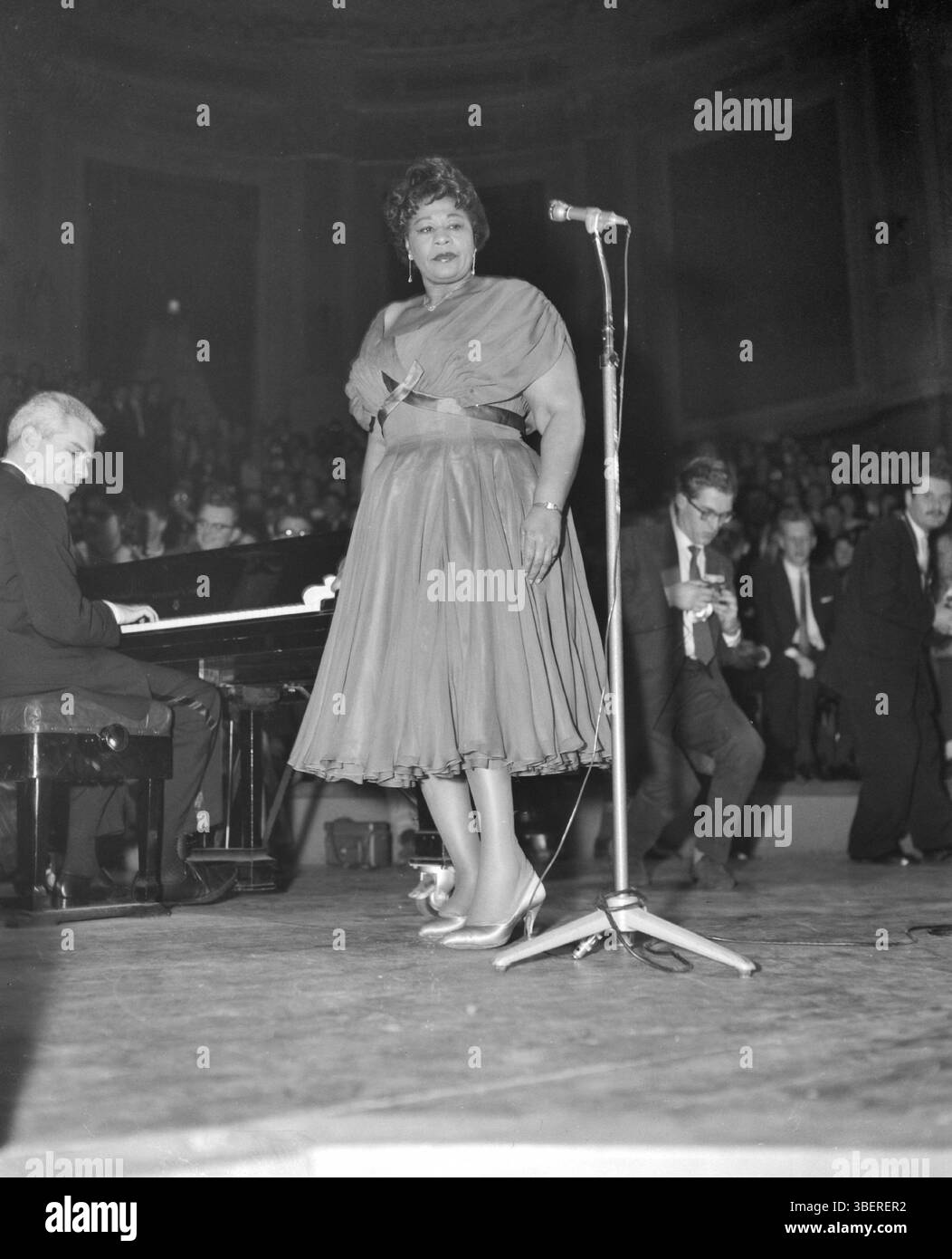 April 11, 1959,  Amsterdam Netherlands. In the series "Jazz at the Philharmonica" in the Concertgebouw, performance by singer Ella Fitzgerald. Ella Fitzgerald singing, behind the piano Lou Levy . Archive Photograph of American Jazz Musicians.  Source: Nationaal Archief Stock Photo
