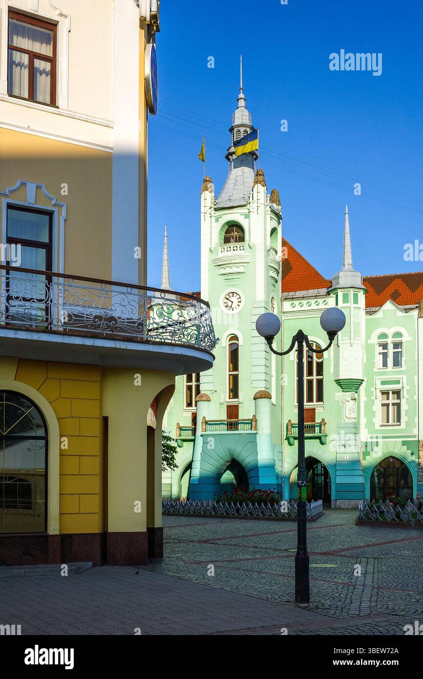 mukachevo, ukraine - jun 16 2012: city council of the old town in morning light. green building with clock tower. popular travel attraction in the cit Stock Photo
