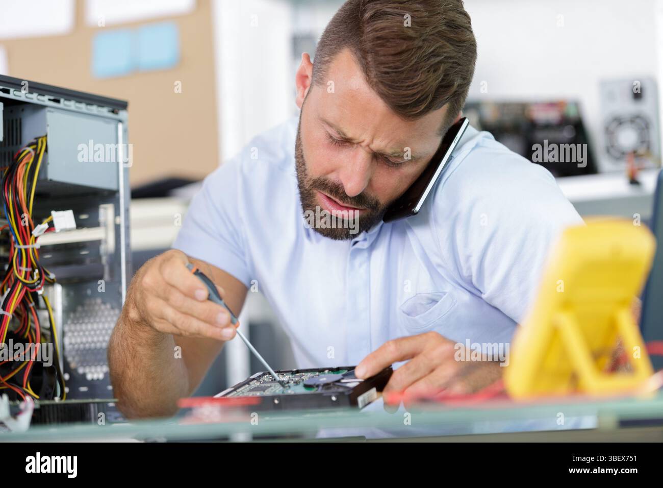 an engineer on the phone repairs a pc computer Stock Photo
