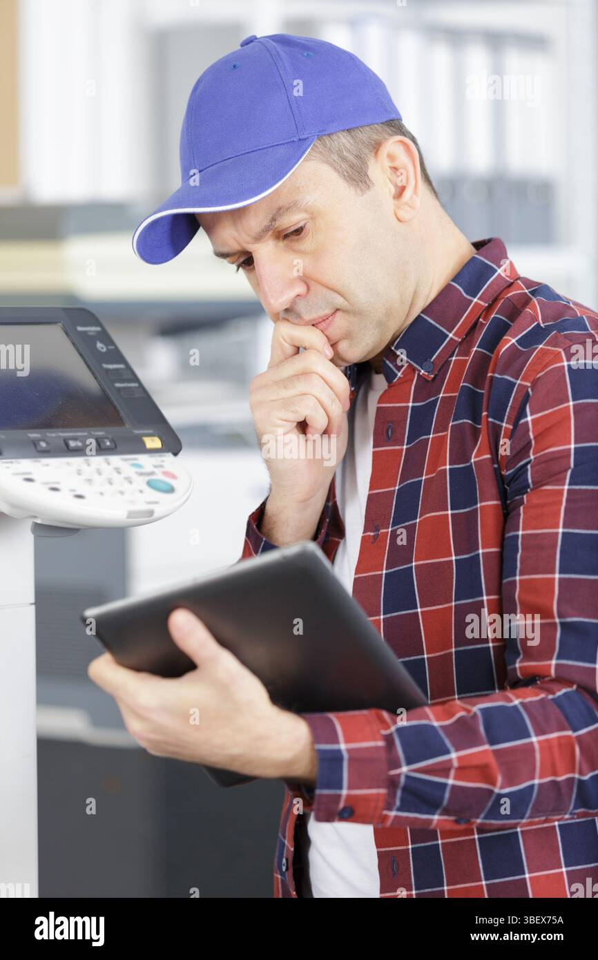 technician using a tablet to fix a printer Stock Photo
