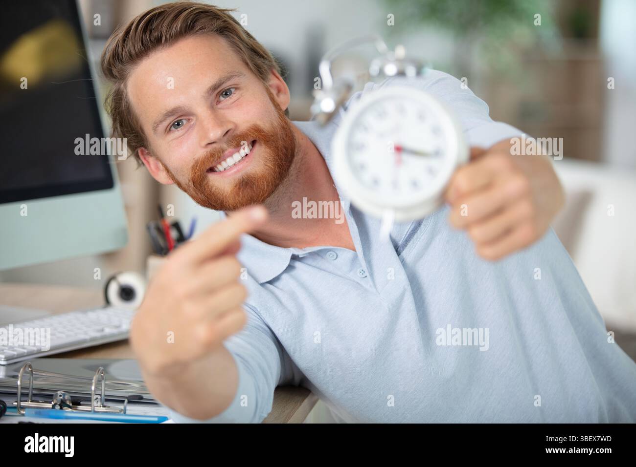 young male contractor repairing alarm clock at workshop Stock Photo