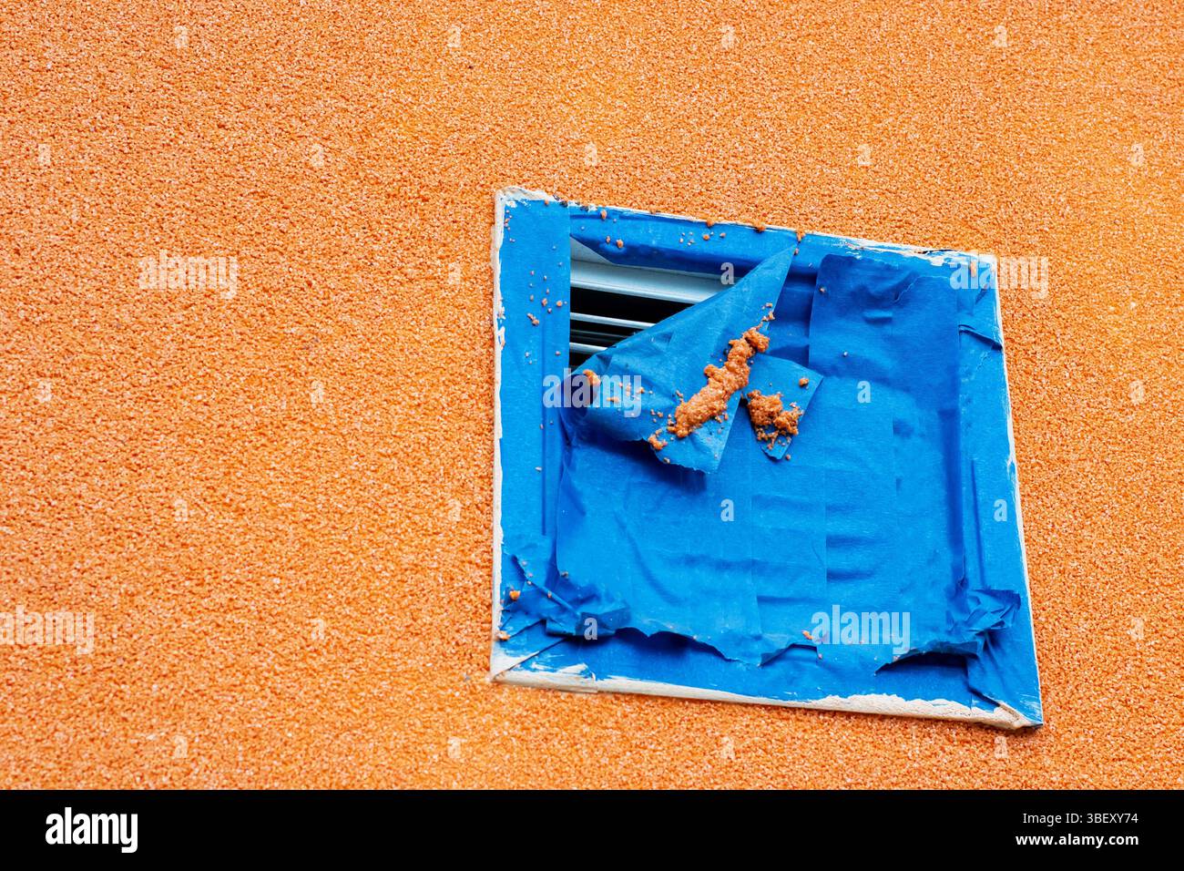 There is an orange wall that features a blue square painted prominently on its surface, adding a vibrant contrast to the setting Stock Photo