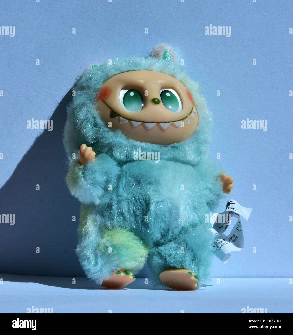 A playful Labubu toy figure in a fluffy blue monster costume with big ...