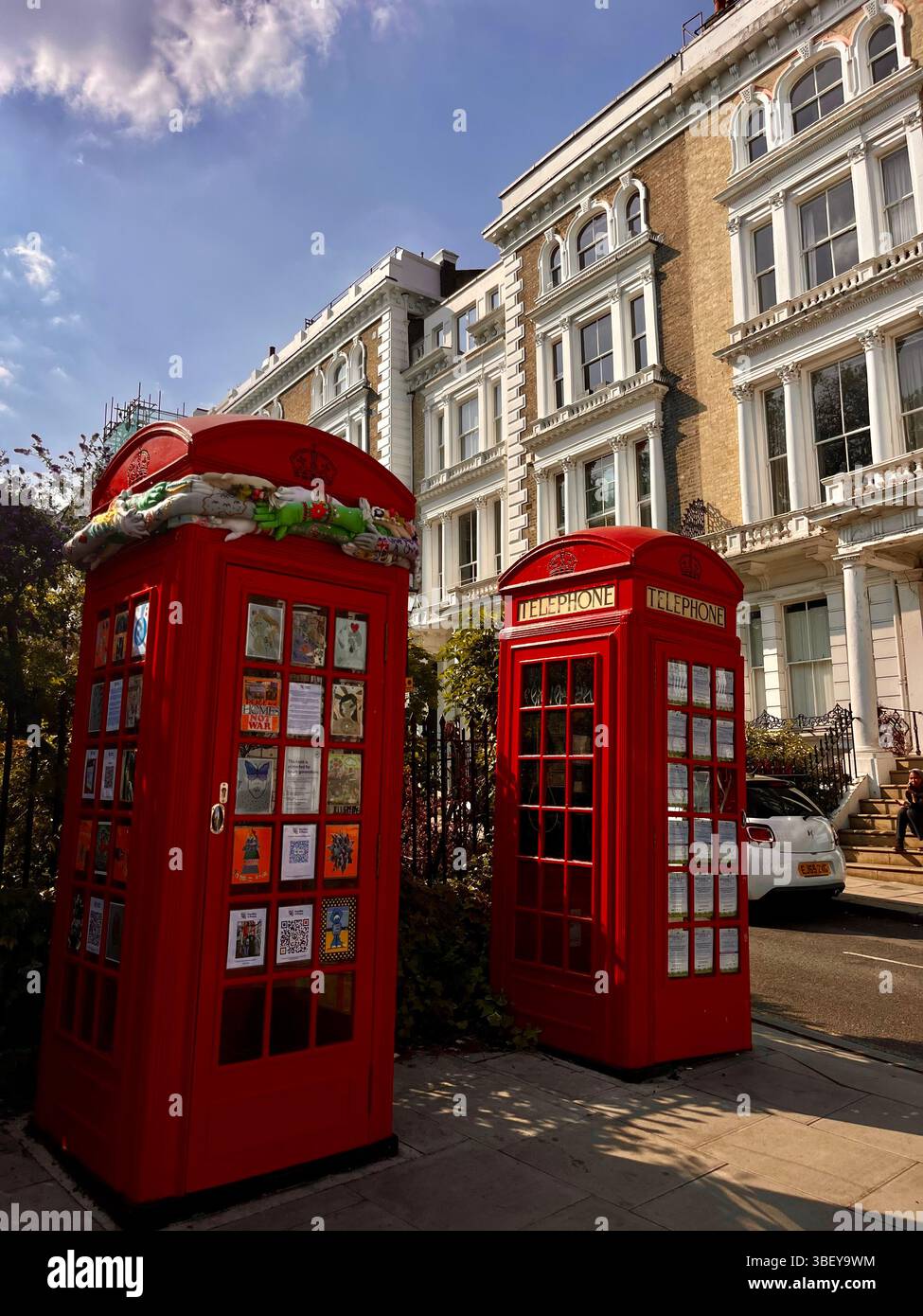 A pair of iconic red phone booth in Primrose Hill, London City, England, United Kingdom, Europe on a sunny day in Spring. - Smartphone Captured Stock Image